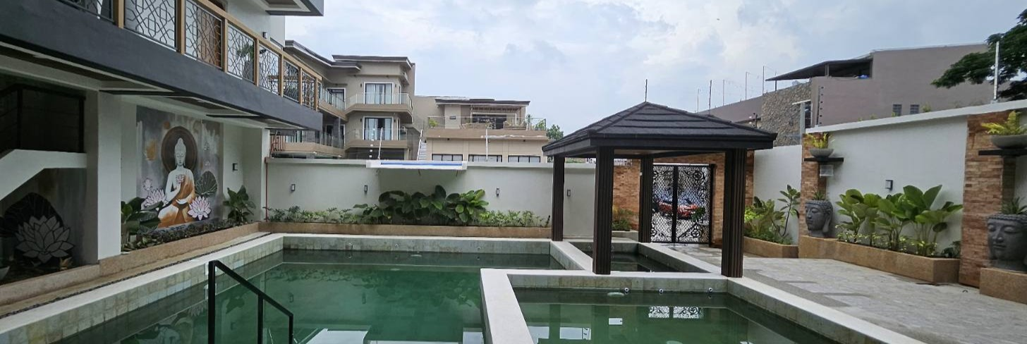 Wide view across the pools toward the pavilion, Buddha mural and planted courtyard walls.